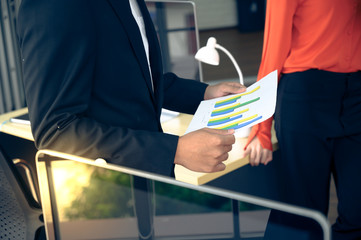 Businessman with graph paper at office workplace.