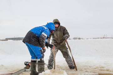 Slingers in protective overalls start a sling under the ice block