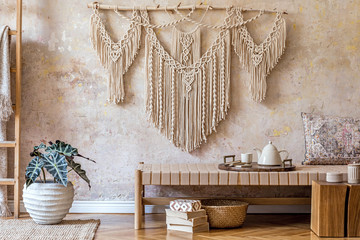 Obraz premium Interior design of stylish living room with beige chaise longue, beautiful macrame, wooden cube, ladder, plants, tea pot on the tray and elegant personal accessories. Oriental concept of home decor.