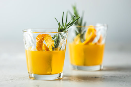 Two glasses of honey bourbon cocktail with rosemary simple syrup or homemade whiskey sour cocktail drink with orange and rosemary decoration orange peel