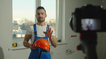 Builder stands with helmet and talks on camera