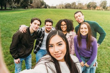 Group of young friends at the park taking a selfie on a meadow with the smart phone - Six people have fun together - Multiracial group