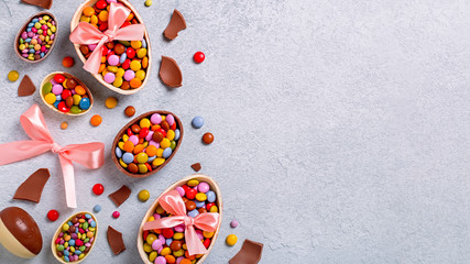 Chocolate Easter eggs and candy on concrete table, festive Easter frame flat lay, copy space. Easter card with traditional sweet treats on grey table top. Sweet Easter concept