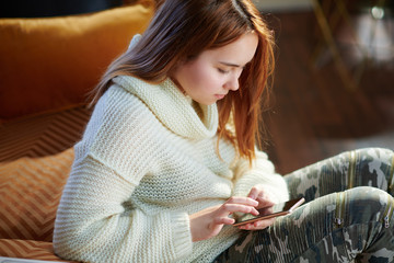 teenage girl in modern house in sunny winter day writing sms