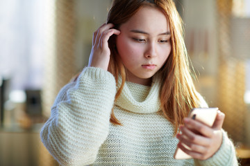 concerned modern teenage girl with smartphone texting