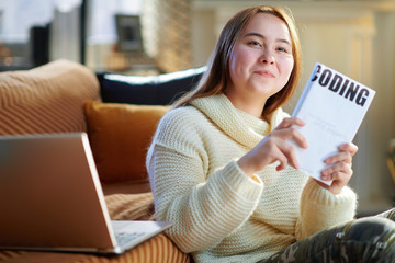 happy young woman with laptop showing educational coding book