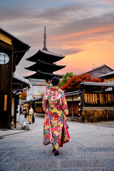 woman holding retro umbrella in old fashion style traditional kimono, walks  in the middle  park of garden village in autumn, travel and visit japan on incoming sport event