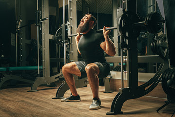 Fototapeta na wymiar Fit man doing squats in a training machine