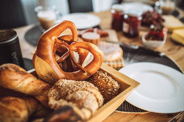 Fresh warm pastries on the morning table - pretzel and rolls in a basket