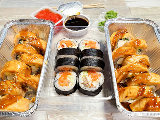 Delicious sushi sets are served in foil packaging on an isolated background, table.