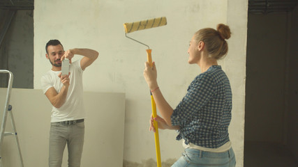 Man makes a photo of woman with roller