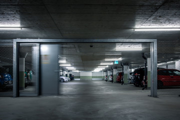 Gated underground parking. Cars parked in a garage with no people. Many cars in parking garage...
