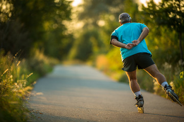 Senior man skating outdoors on a lovely summer evening. Getting his daily dose of cardio.