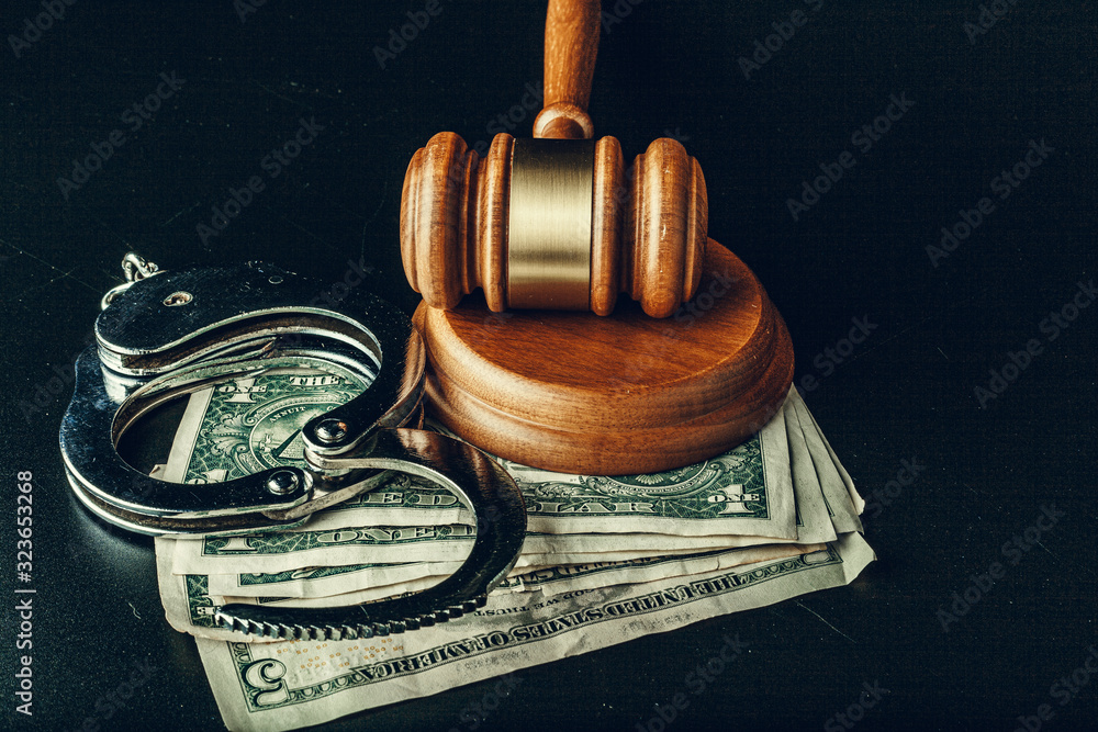 Wall mural bribe concept. dollar banknotes, handcuffs and gavel on dark black table