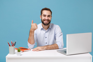 Smiling young bearded man in light shirt sit work at white desk with pc laptop isolated on pastel...