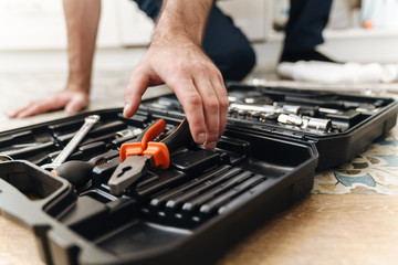 Plumber work in uniform indoors with case with equipment.