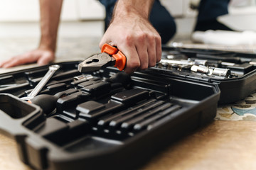 Plumber work in uniform indoors with case with equipment.