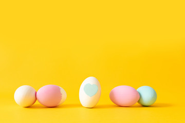 Happy easter background. Decorated white, pink and blue eggs on a yellow background.