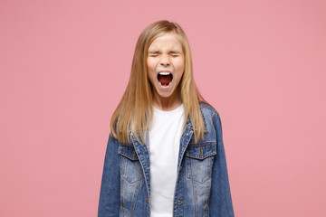 Crazy little blonde kid girl 12-13 years old in denim jacket isolated on pastel pink wall...