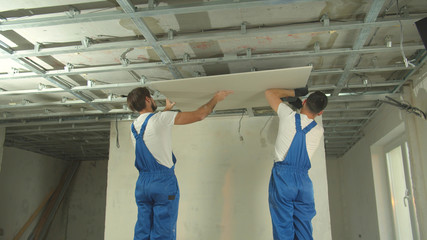 Repairmen in uniform install the panel on the ceiling