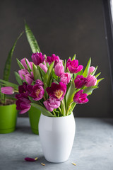 bouquet of tulips in white vase on stone grey background