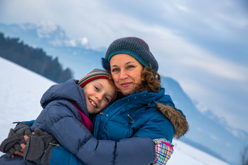 Fototapeta na wymiar Caring mother hugging her daughter in the snow