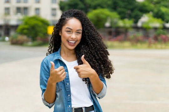 Brazilian girl with curly hair and braces showing both thumbs up