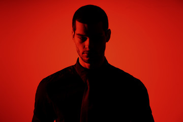 Silhouette of a young confident handsome businessman wearing black shirt in red light