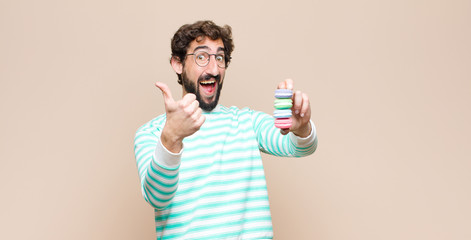 young man with macaroons against flat wall