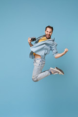 Fototapeta na wymiar Happy traveler tourist man in yellow casual clothes with photo camera isolated on blue background. Male passenger traveling abroad on weekend. Air flight journey concept. Jumping doing winner gesture.