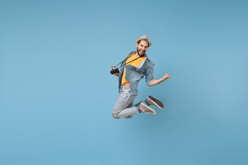 Fototapeta na wymiar Joyful traveler tourist man in yellow casual clothes with photo camera isolated on blue background. Male passenger traveling abroad on weekend. Air flight journey concept Jumping doing winner gesture.