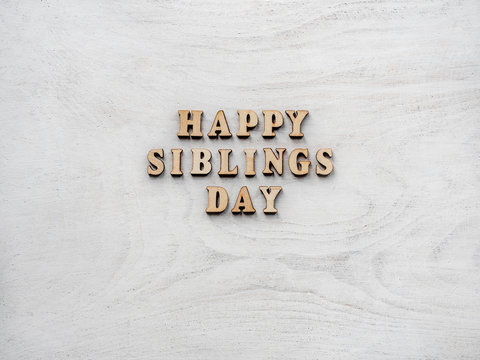 Wooden Letters Of The Alphabet In The Form Of The Words SIBLING DAY On The Table. Beautiful Card. Isolated Background, Wooden Surface. Congratulations For Relatives, Friends And Colleagues