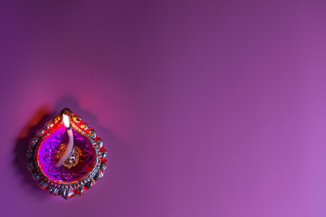 burning decorated ceramic oil lamp diya, on Happy Diwali, Shubh Diwali meaning with beautiful pink background, copy space