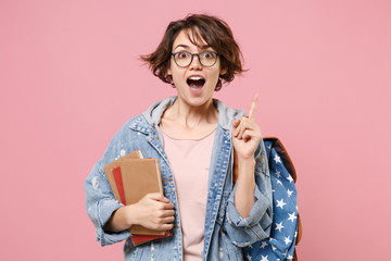 Excited girl student in denim clothes glasses backpack isolated on pastel pink background....