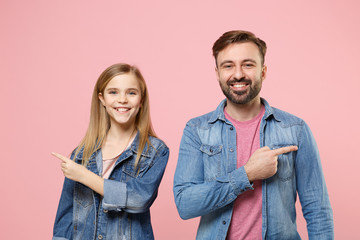Smiling bearded man in casual clothes with cute child baby girl. Father little kid daughter isolated on pastel pink background. Love family parenthood childhood concept. Pointing index fingers aside.