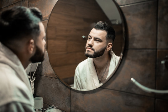Fashion portrait bearded groom looking in mirrow
