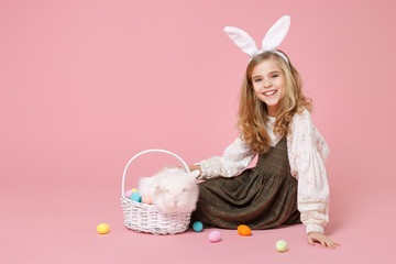 Little pretty blonde kid girl 11-12 years old in light spring dress hold fluffy white bunny rabbit,...
