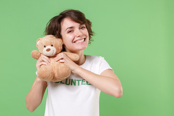 Funny young brunette woman in white volunteer t-shirt isolated on pastel green background in...
