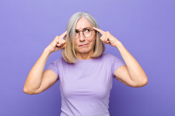 senior or middle age pretty woman looking concentrated and thinking hard on an idea, imagining a...