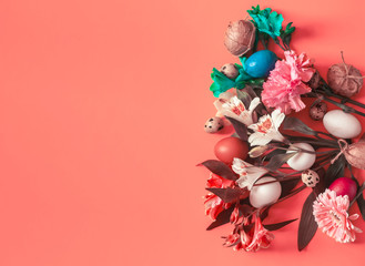 Colorful easter eggs and spring flower bouquet decoration on the vibrant red paper background. Top view of bright spring background. Copy space on the left side
