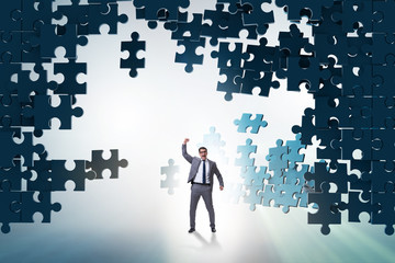 Businessman breaking the wall of jigsaw puzzle