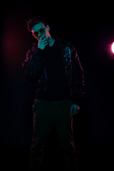 Fototapeta na wymiar Portrait of a fashion trend male model neon gel light in studio on a dark black background