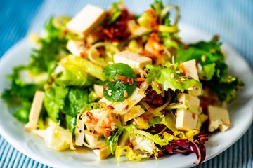 Mixed green salad with feta, dried tomato and sesame seeds.