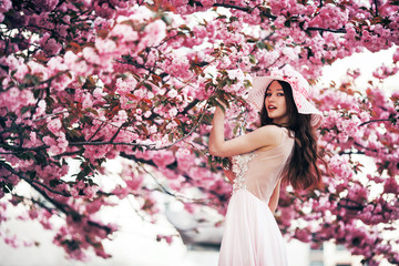 girl stands on a background of a blossoming tree in spring