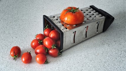 A tomato went through a cheese grater and little cherry tomato comes out still life food photography