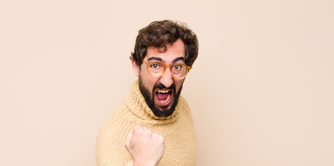 young cool man shouting aggressively with annoyed, frustrated, angry look and tight fists, feeling...