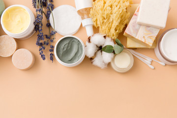 beauty, spa and wellness concept - close up of crafted soap bars, natural bristle wooden brush, body butter with sponge and herbs on beige background