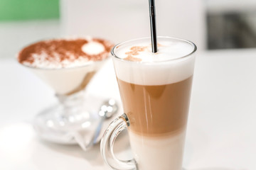 coffee latte with frothy milk in tall glass, rustic style, white background