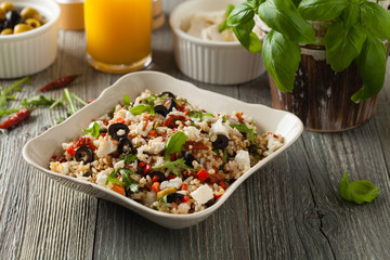 Trendy lunch with red rice, a mix of groats and vegetables. Front view. Served in white bowl on grey wooden background.