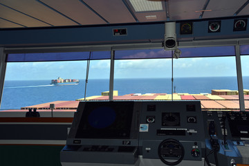View of the control console with steering  wheel, on the navigational bridge of the cargo ship,...